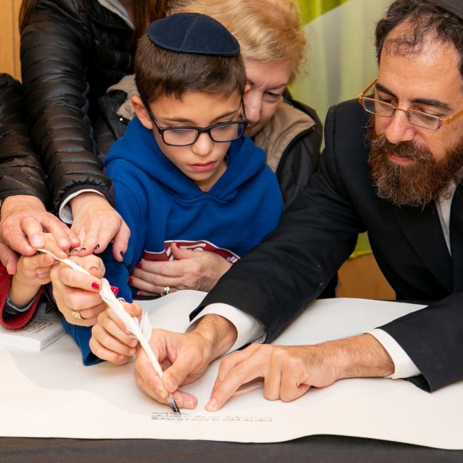 Group of people writing a letter in the Torah